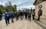 uczestnicy konferencji oraz pracownicy lasów stoja przed ośrodkiem hodowli głuszca (budynek z bali)