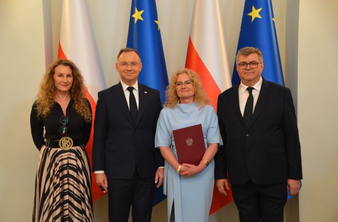 prof stanek-tarkowska stoi obok prezeydenta RP, w ręku trzyma dyplom, obok stoją dwie inne osoby, w tle flagi polski i UE