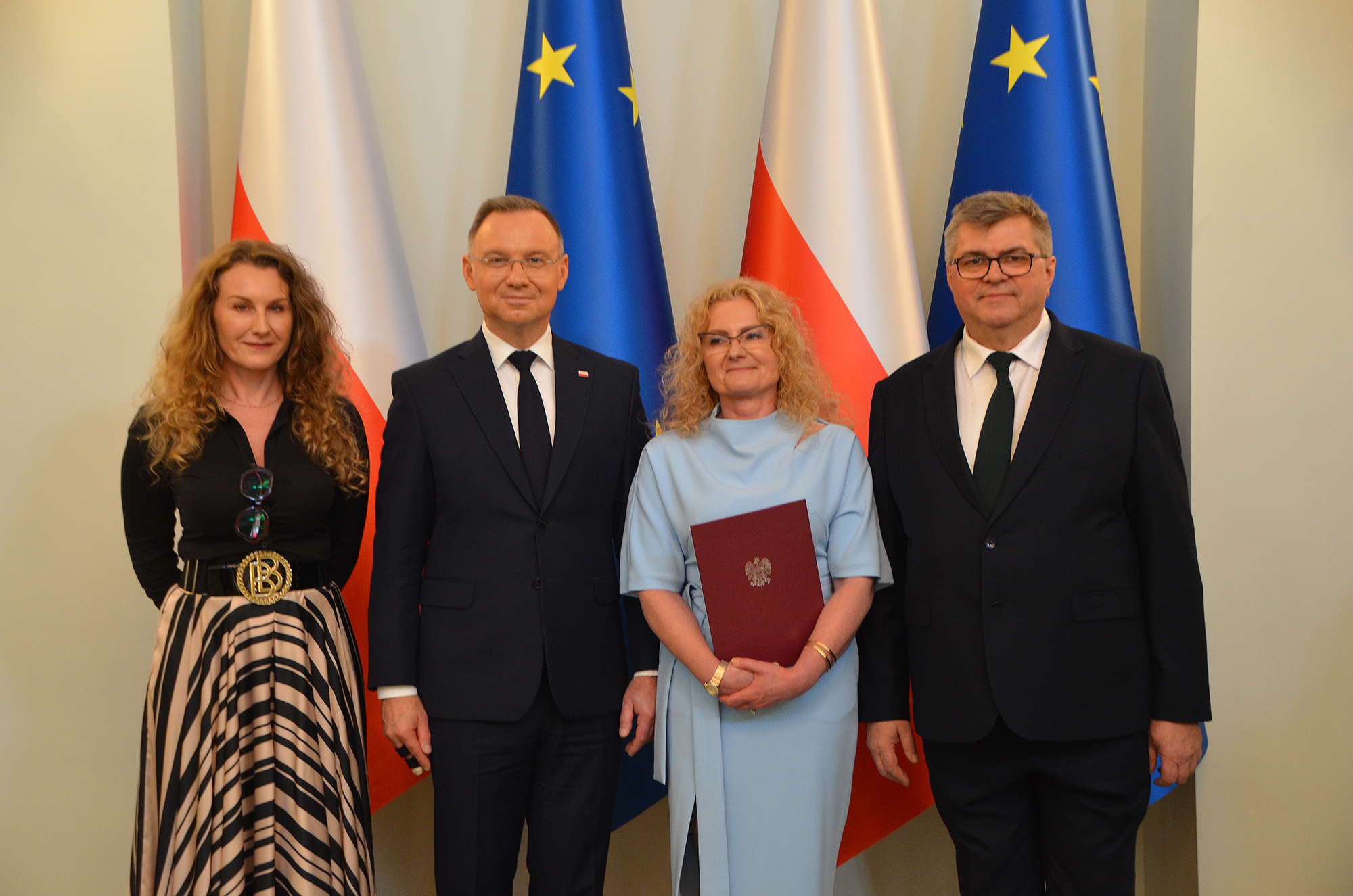 prof stanek-tarkowska stoi obok prezeydenta RP, w ręku trzyma dyplom, obok stoją dwie inne osoby, w tle flagi polski i UE